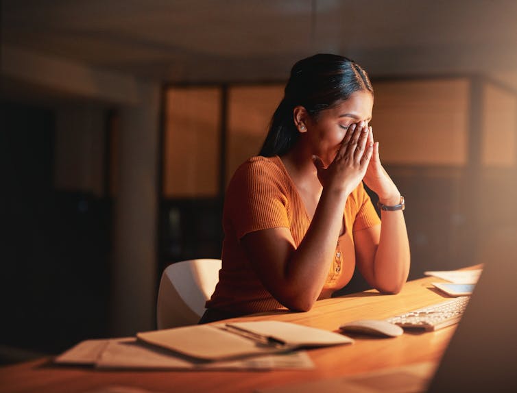 Young business woman sitting alone at the office at night and feeling stressed